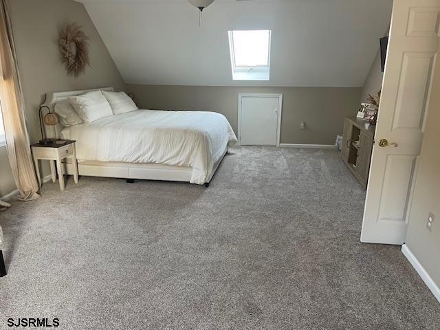 bedroom with vaulted ceiling, carpet floors, and multiple windows