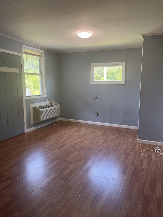 spare room featuring ornamental molding, dark hardwood / wood-style flooring, an AC wall unit, and a healthy amount of sunlight