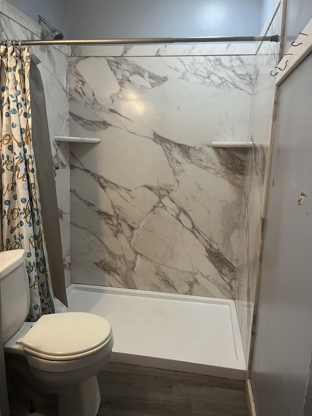 bathroom with hardwood / wood-style flooring, a shower with curtain, and toilet