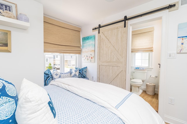 328 83rd St, Stone Harbor, NJ 08247 - bedroom with a barn door, connected bathroom, and wood finished floors