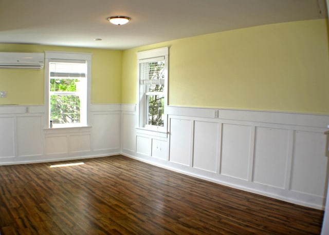 empty room featuring an AC wall unit and dark wood-type flooring