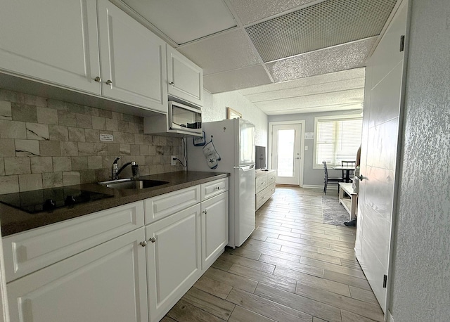 9103 Atlantic Ave Unit 413, Wildwood Crest, NJ 08260 - kitchen with black electric cooktop, stainless steel microwave, dark countertops, freestanding refrigerator, and white cabinets