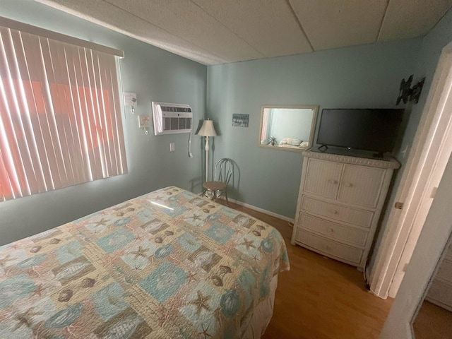 bedroom featuring a paneled ceiling and a wall mounted air conditioner