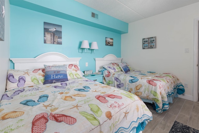 bedroom featuring wood tiled floor, a textured ceiling, and visible vents