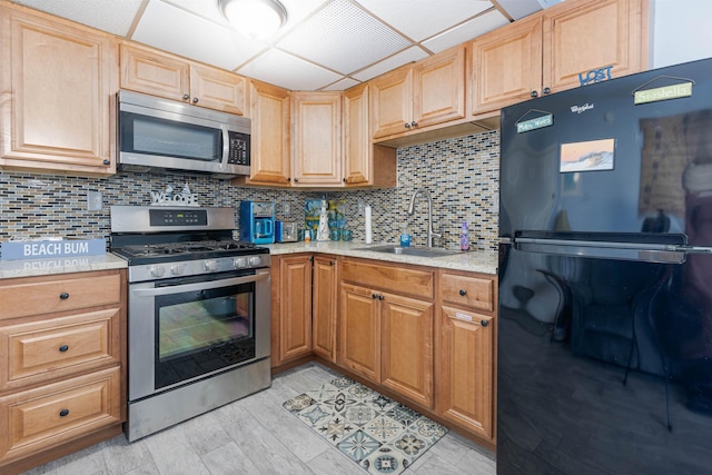 kitchen featuring decorative backsplash, light countertops, a sink, and appliances with stainless steel finishes