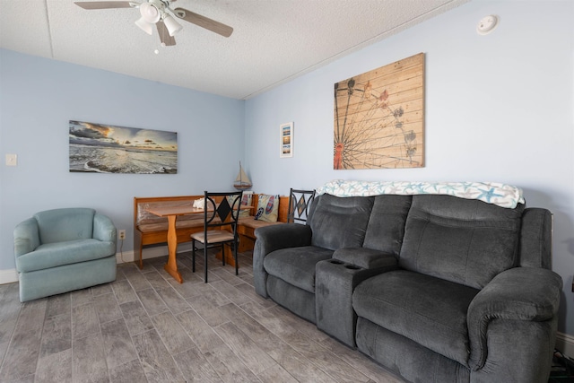 living room with wood finished floors, a textured ceiling, a ceiling fan, and baseboards