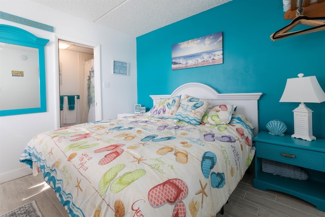 bedroom with a textured ceiling, wood finish floors, and baseboards