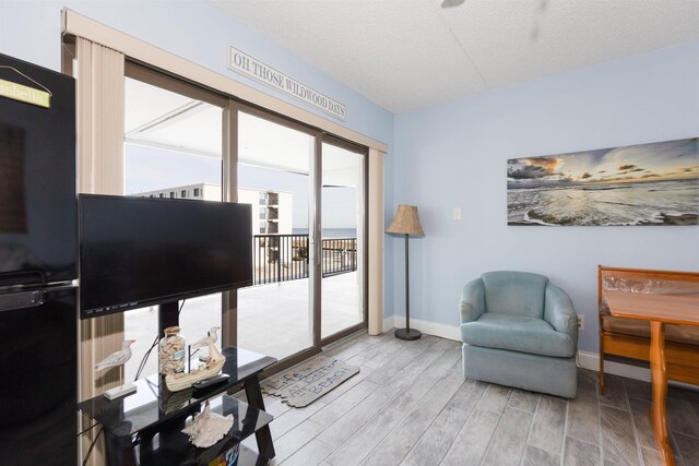 sitting room featuring wood finished floors, a textured ceiling, and baseboards