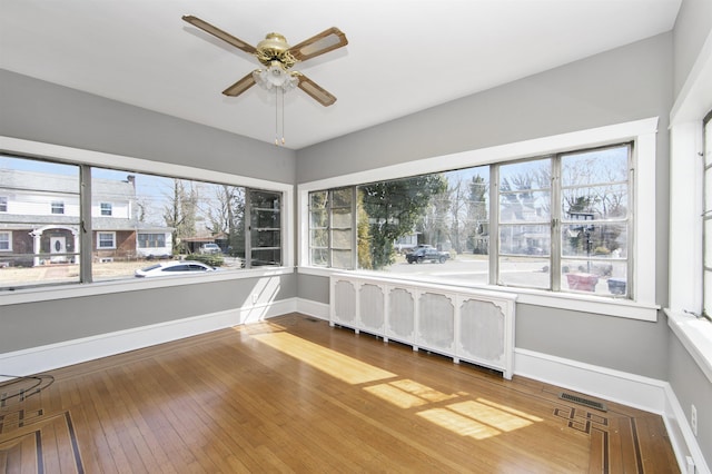 unfurnished sunroom with ceiling fan
