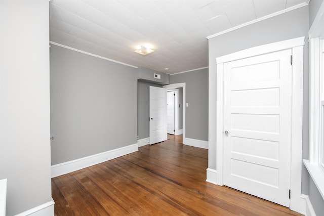 empty room featuring crown molding, baseboards, and hardwood / wood-style flooring