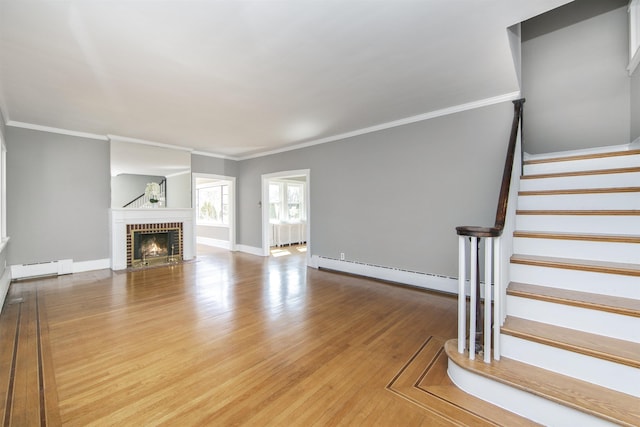 unfurnished living room featuring wood finished floors, baseboards, a fireplace, stairs, and baseboard heating