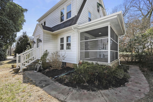 view of property exterior with fence, a shingled roof, and a sunroom