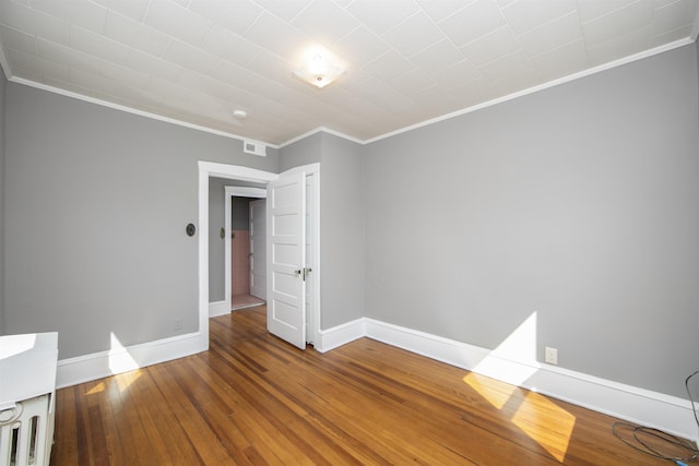 spare room featuring baseboards, crown molding, and hardwood / wood-style flooring