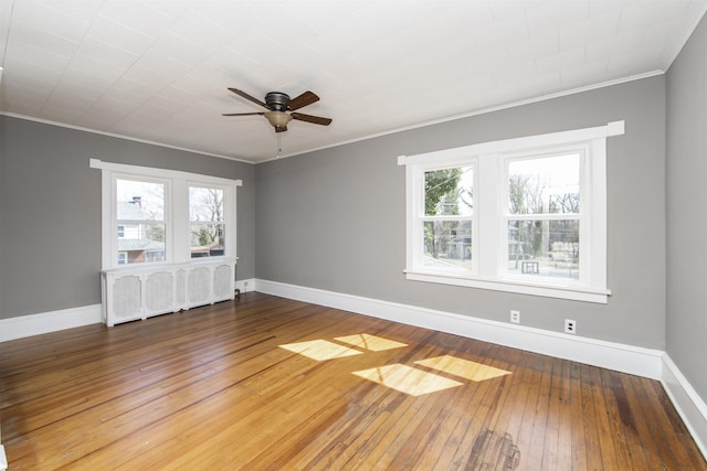 spare room featuring baseboards, radiator heating unit, ceiling fan, hardwood / wood-style flooring, and crown molding