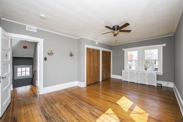unfurnished room featuring visible vents, a ceiling fan, hardwood / wood-style flooring, crown molding, and baseboards