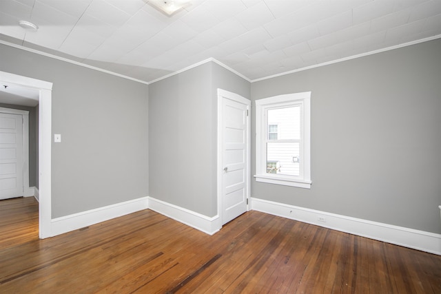 empty room with ornamental molding, baseboards, and hardwood / wood-style flooring