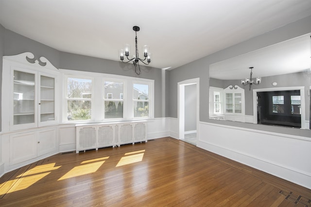 unfurnished dining area with visible vents, a chandelier, radiator heating unit, and hardwood / wood-style flooring