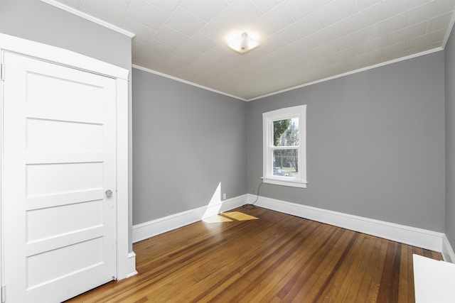 spare room featuring hardwood / wood-style flooring, baseboards, and ornamental molding