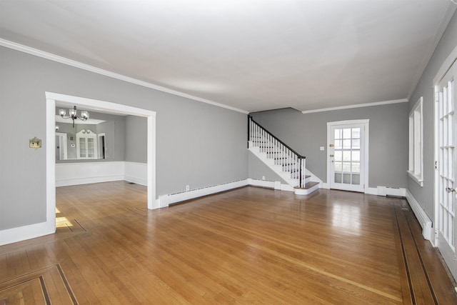 unfurnished living room featuring a notable chandelier, baseboard heating, stairs, and hardwood / wood-style flooring