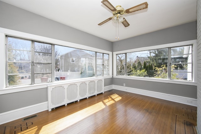 unfurnished sunroom with radiator, visible vents, and ceiling fan