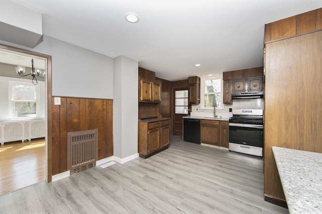 kitchen with black dishwasher, under cabinet range hood, gas range, light wood-type flooring, and a chandelier