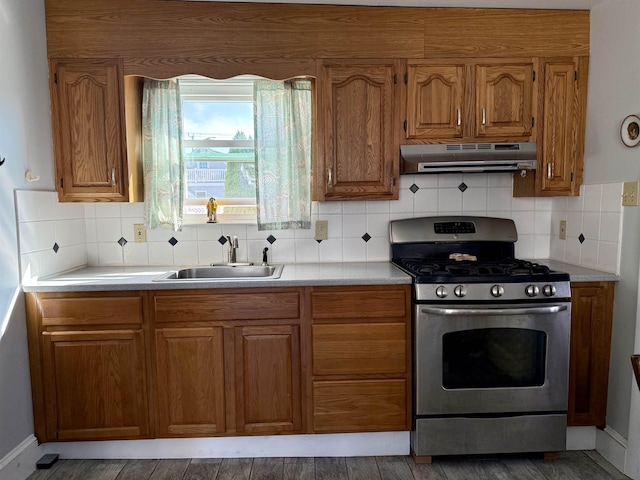 207 W Maple Ave, Wildwood, NJ 08260 - kitchen with stainless steel gas stove, under cabinet range hood, a sink, brown cabinets, and light countertops