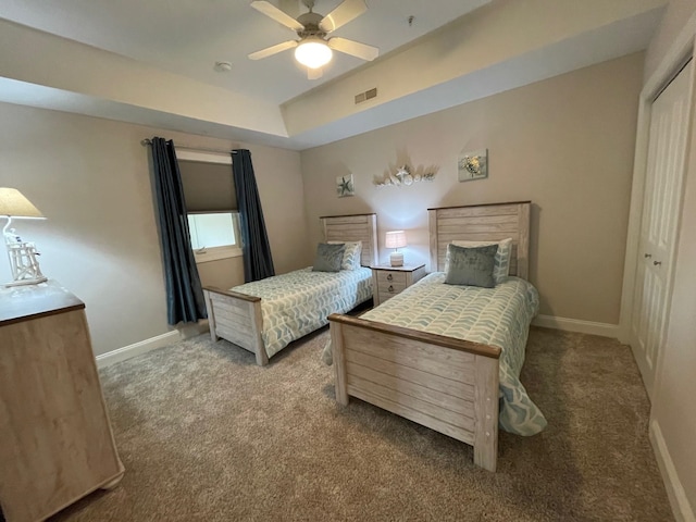 bedroom with ceiling fan, a closet, carpet, and a raised ceiling