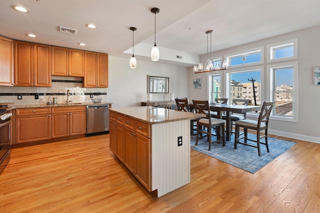 kitchen with light hardwood / wood-style floors, pendant lighting, appliances with stainless steel finishes, and a center island