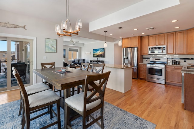 dining room featuring light hardwood / wood-style floors and ceiling fan with notable chandelier