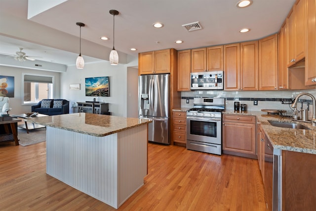 kitchen with ceiling fan, pendant lighting, sink, light stone countertops, and appliances with stainless steel finishes