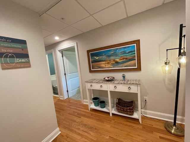 hallway featuring a paneled ceiling and light hardwood / wood-style flooring