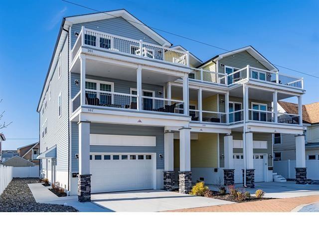 view of front of property with a balcony, an attached garage, fence, and driveway