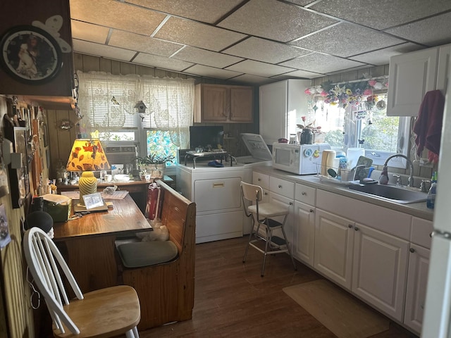 kitchen with white cabinets, wood walls, wood-type flooring, and sink