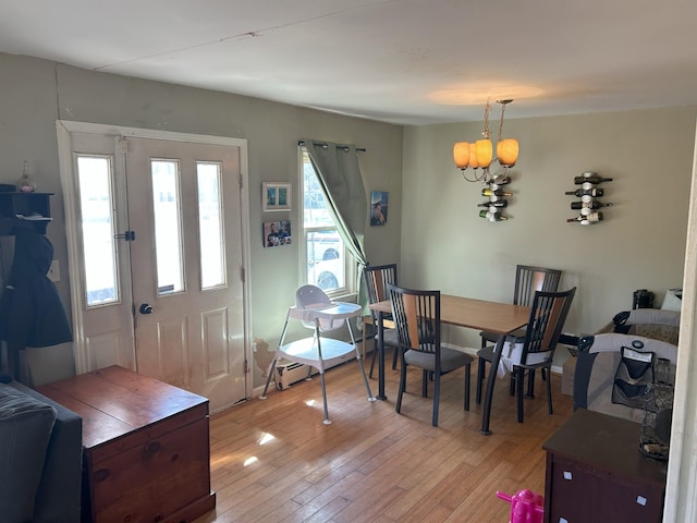 dining space featuring a wealth of natural light, light wood-type flooring, and a notable chandelier