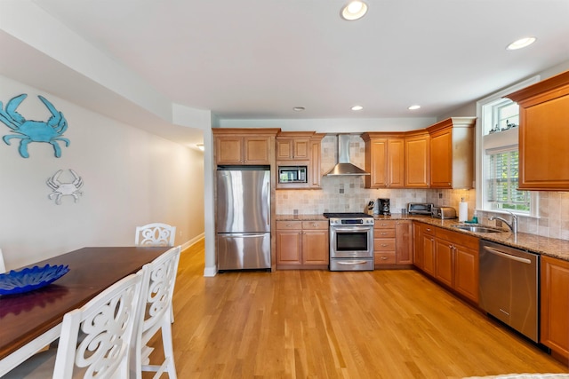 2025 Dune Dr Unit 2025, Avalon, NJ 08202 - kitchen featuring appliances with stainless steel finishes, wall chimney exhaust hood, light stone counters, light wood-style flooring, and backsplash