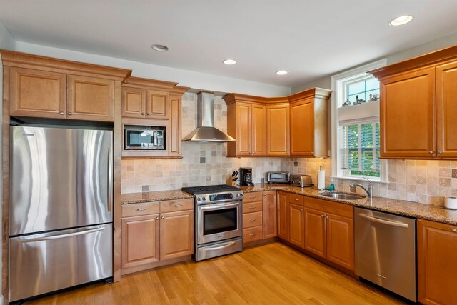 2025 Dune Dr Unit 2025, Avalon, NJ 08202 - kitchen featuring appliances with stainless steel finishes, wall chimney exhaust hood, light stone counters, light wood finished floors, and decorative backsplash