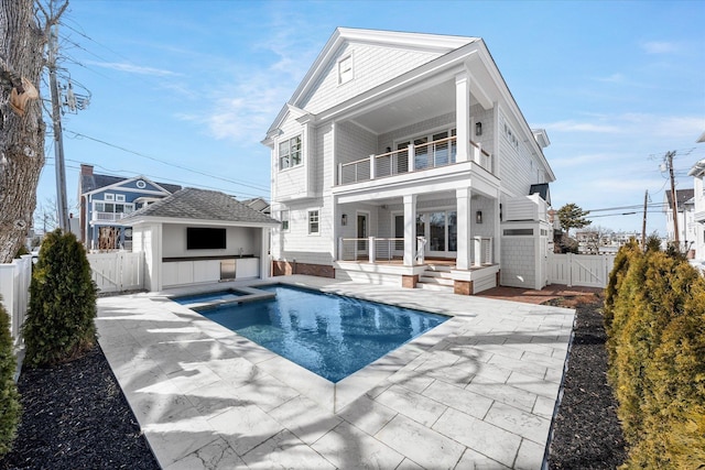 rear view of property with a pool with hot tub, a patio area, an outdoor structure, and a balcony