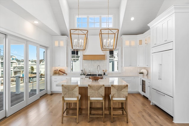 kitchen with a notable chandelier, a kitchen island, white cabinets, and decorative backsplash