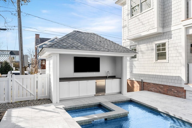 exterior space featuring an in ground hot tub, sink, area for grilling, and a patio area