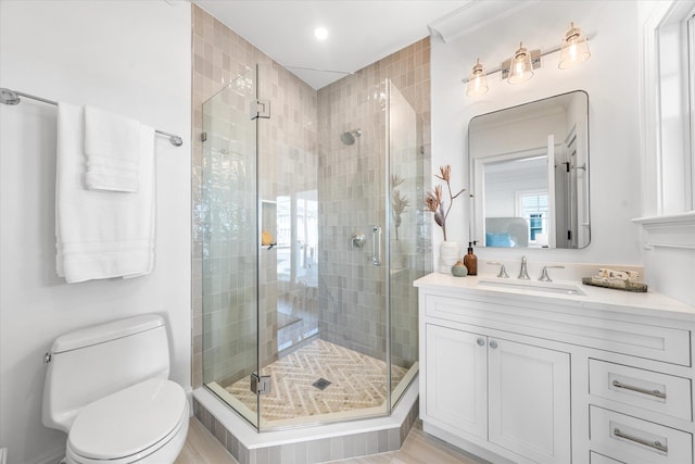 bathroom with a shower with door, vanity, and toilet