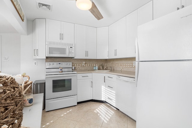 kitchen featuring a sink, light countertops, decorative backsplash, and white appliances