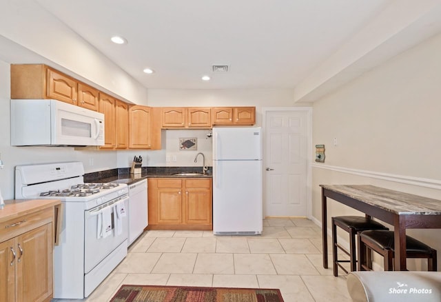 kitchen featuring light tile patterned flooring, white appliances, and sink