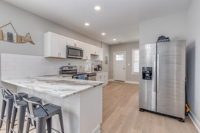 222 E Burk Ave Unit 4, Wildwood, NJ 08260 - kitchen with stainless steel appliances, white cabinetry, a kitchen bar, light stone countertops, and baseboards