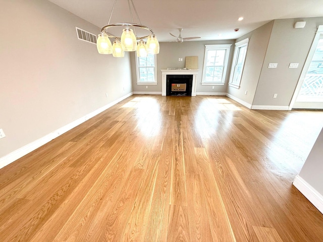 unfurnished living room with visible vents, baseboards, ceiling fan, light wood-type flooring, and a fireplace