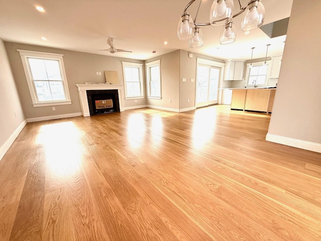 kitchen with white cabinets, a center island, hanging light fixtures, a peninsula, and a sink