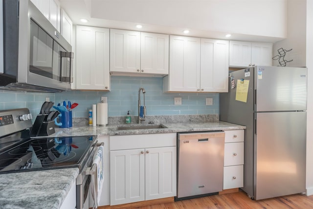 kitchen with stainless steel appliances, light wood-type flooring, a sink, and white cabinets