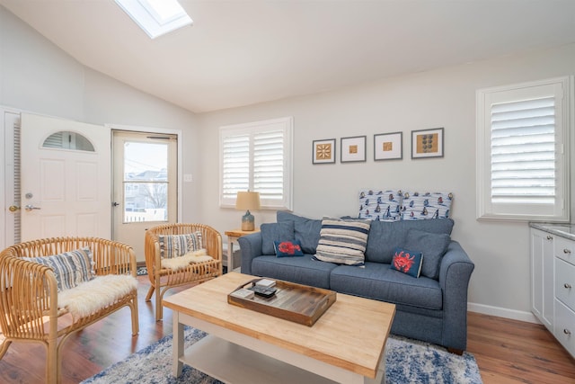 living room featuring lofted ceiling with skylight, light wood-style flooring, and baseboards