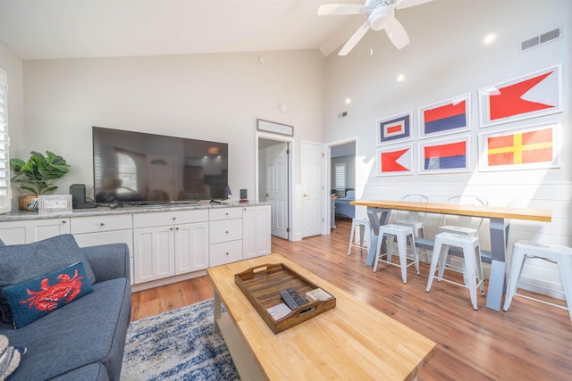 living room featuring ceiling fan, high vaulted ceiling, visible vents, and light wood-style floors