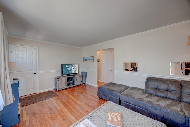 living area with light wood-style flooring, baseboards, and ornamental molding