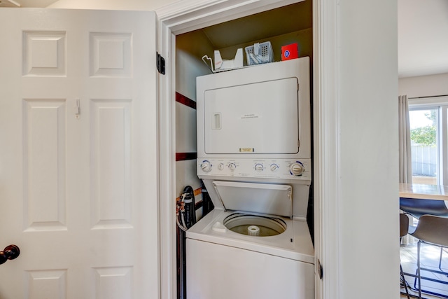 clothes washing area featuring stacked washing maching and dryer and laundry area